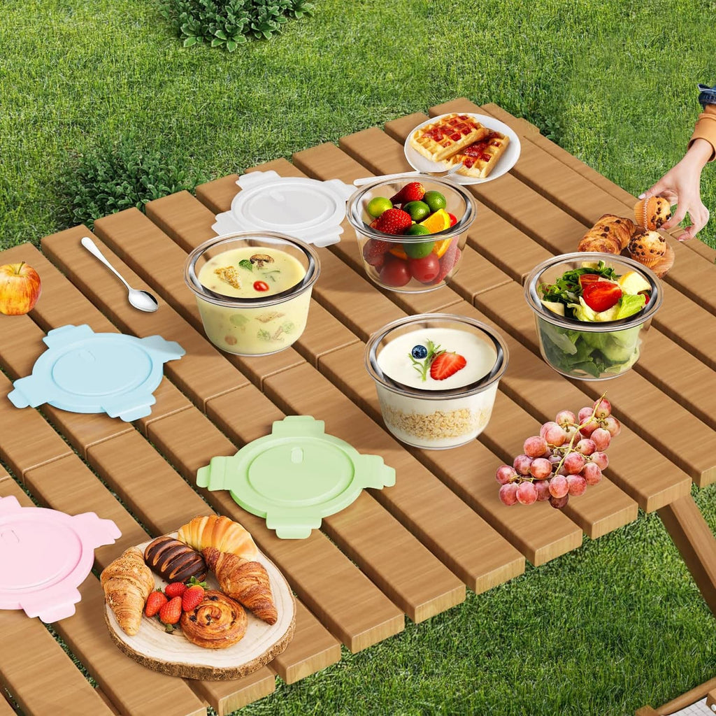 Multiple glass meal prep containers with airtight lids on a wooden picnic table.