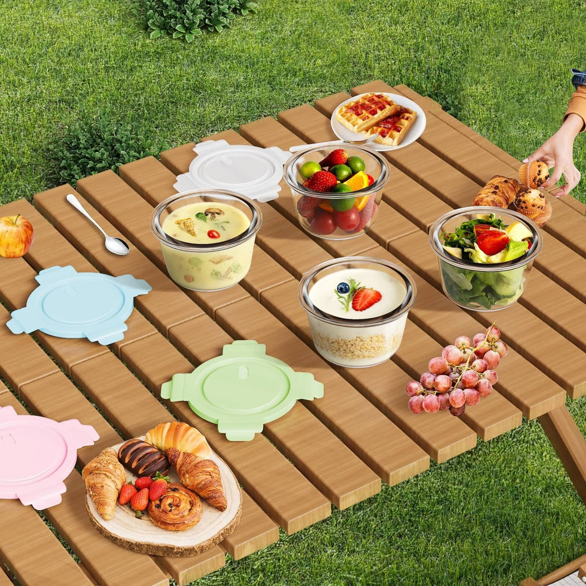 Multiple glass meal prep containers with airtight lids on a wooden picnic table.