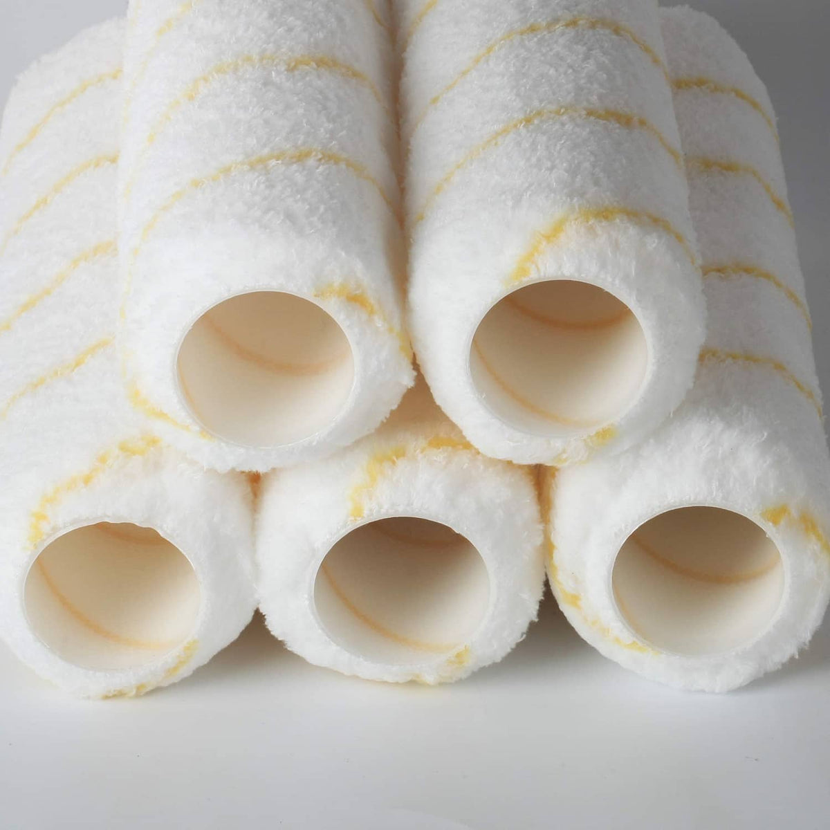 Close-up of paint roller cover ends, white foam sleeves with yellow stripe