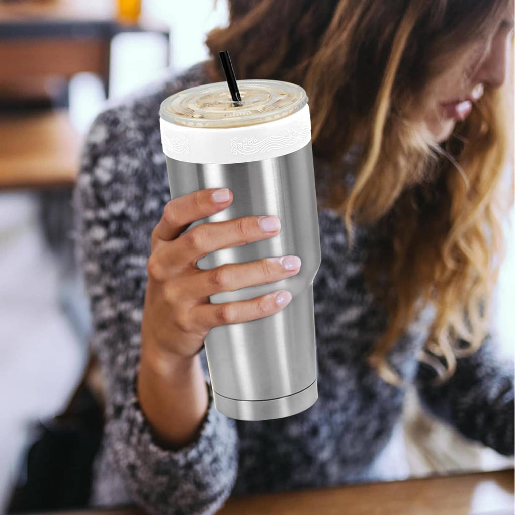 Stainless tumbler with white silicone ring top and straw, in hand
