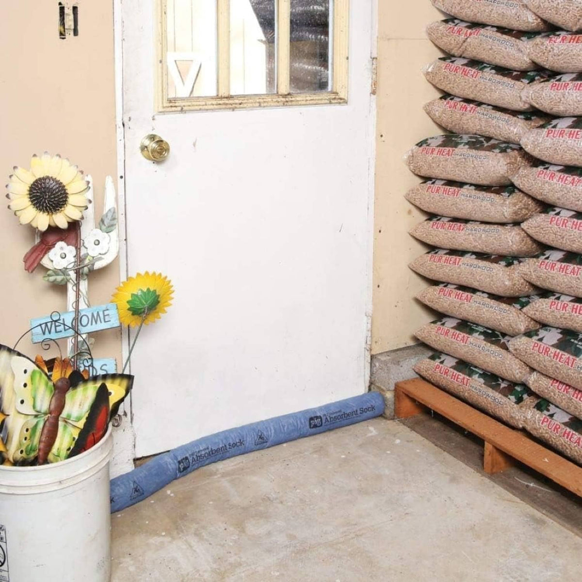 Blue absorbent sock barrier laid in an L-shape on the floor near stacked bags