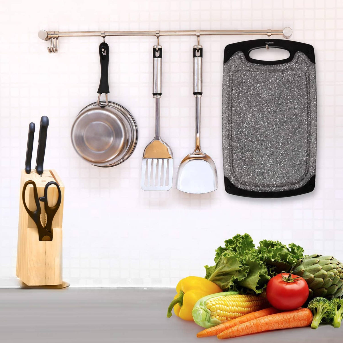 Gray speckled plastic cutting board with black handle, hanging in the kitchen