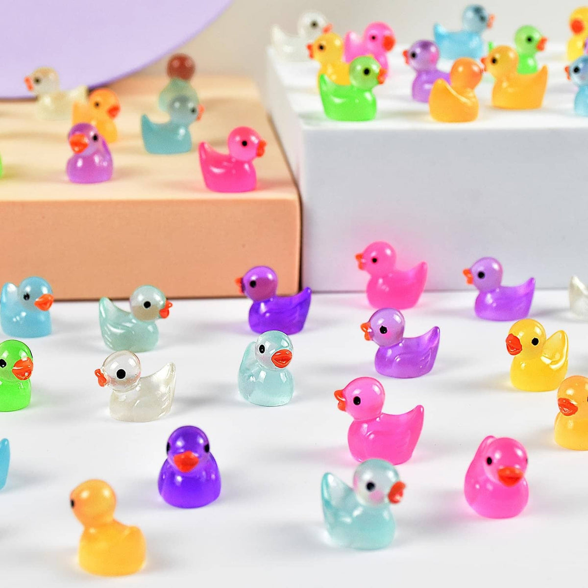 Set of small luminous resin duck figurines in pink, purple, blue, and green
