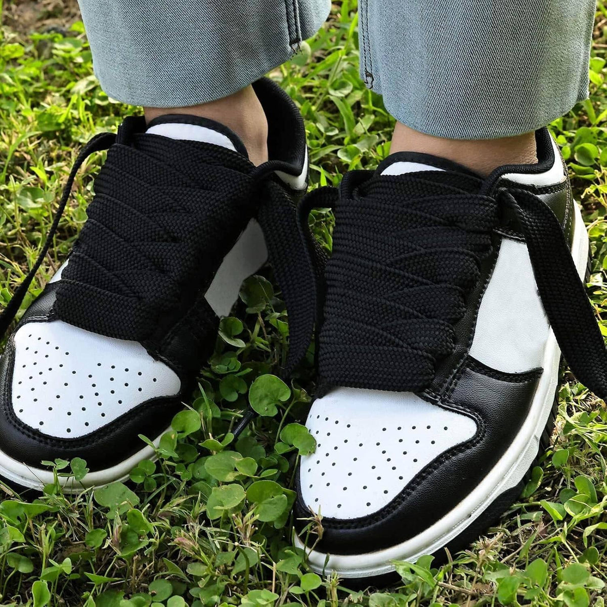 Black thick shoelaces tied on white-and-black sneakers