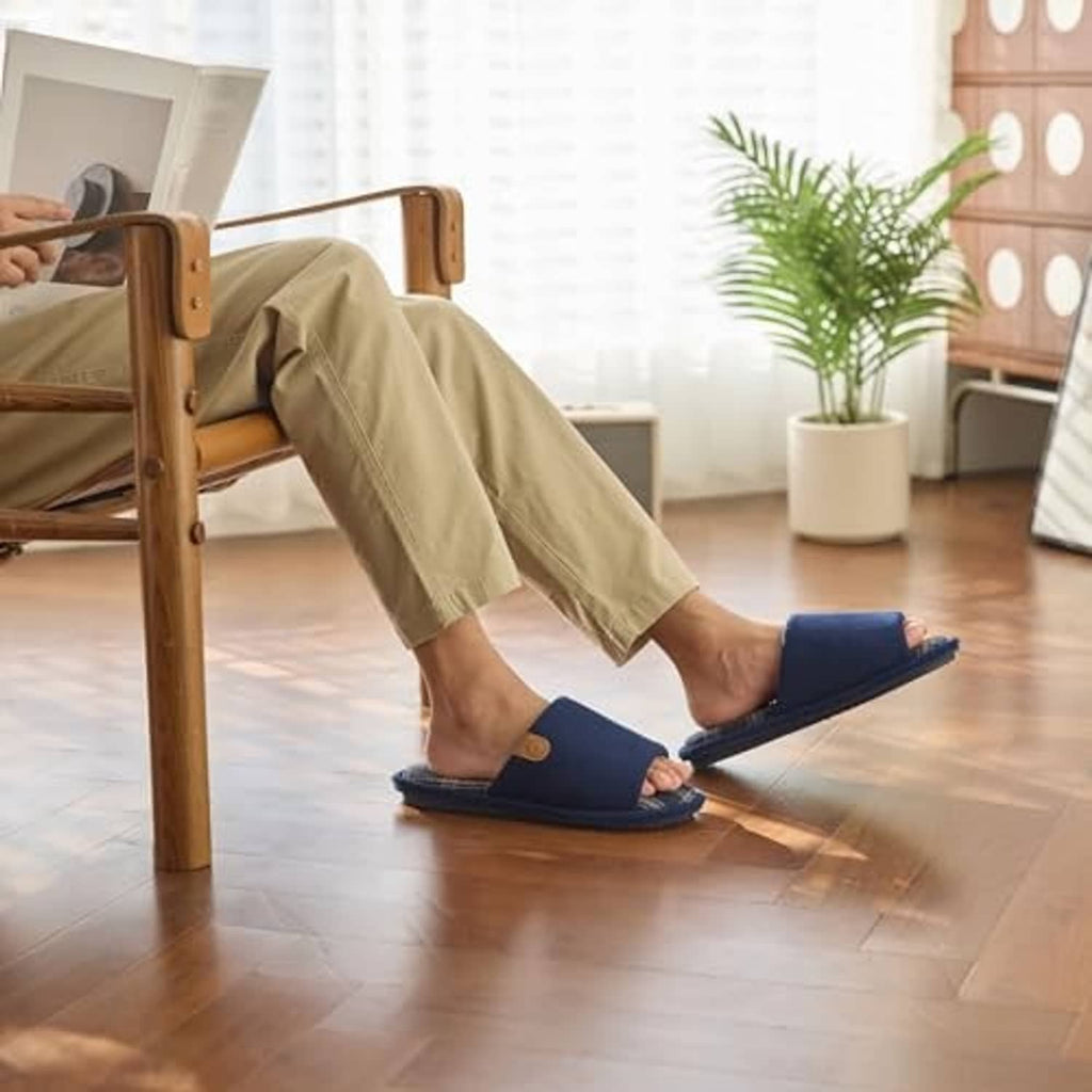 Man wearing dark blue corduroy slip-on slippers with plaid-lined interior