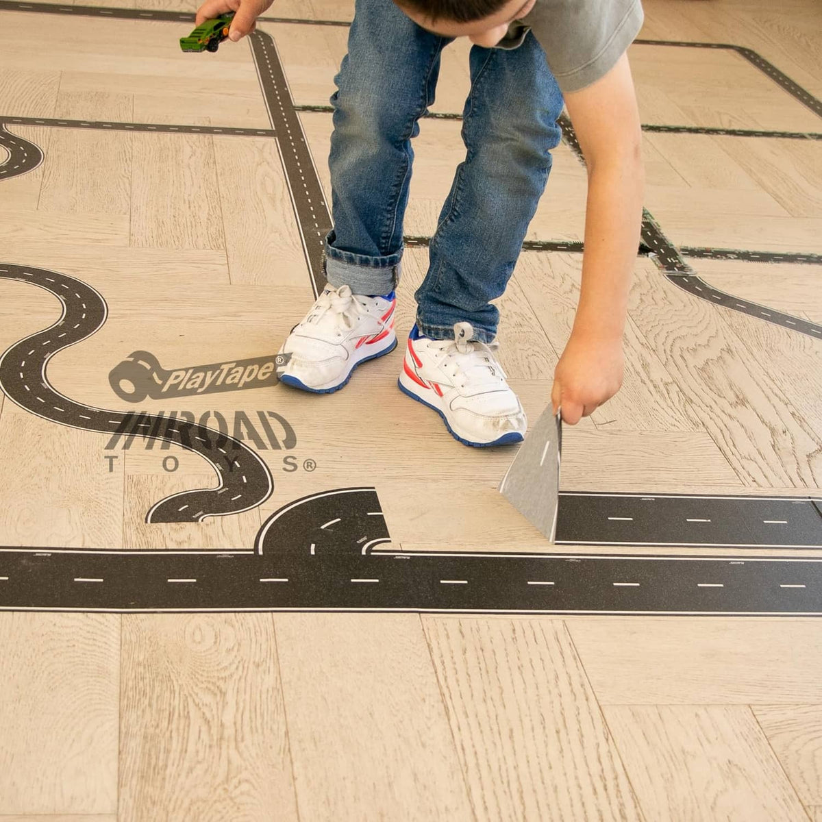 Road tape installation on wood floor with black curved road section and white lane markings
