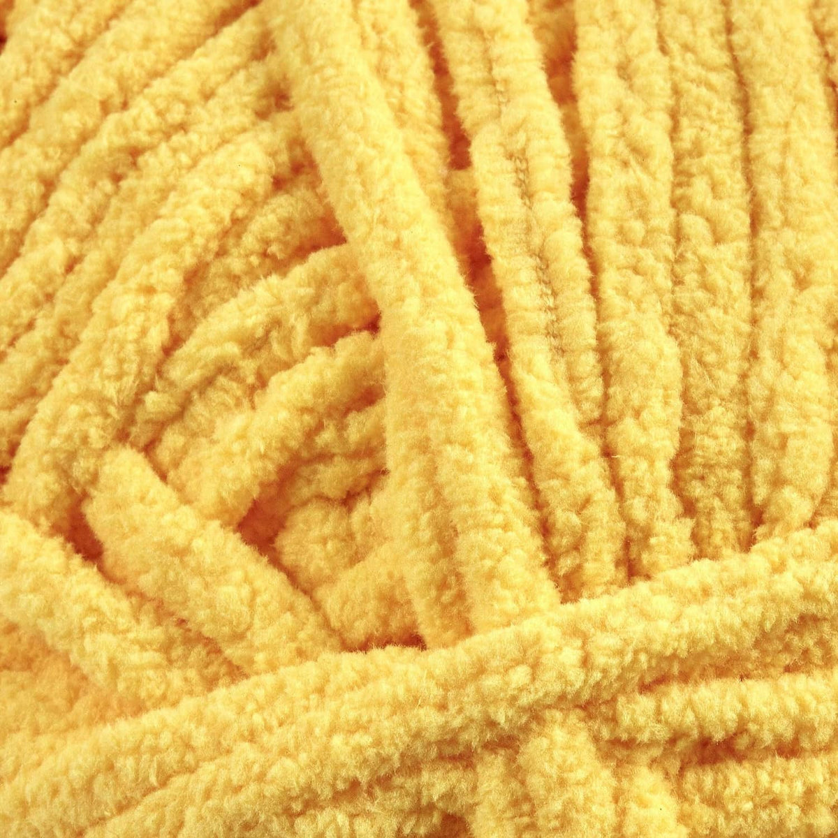 Close-up of yellow chenille yarn texture with thick, soft pile strands