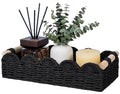 Black woven toilet paper storage basket with wood-capped handles and assorted bathroom items