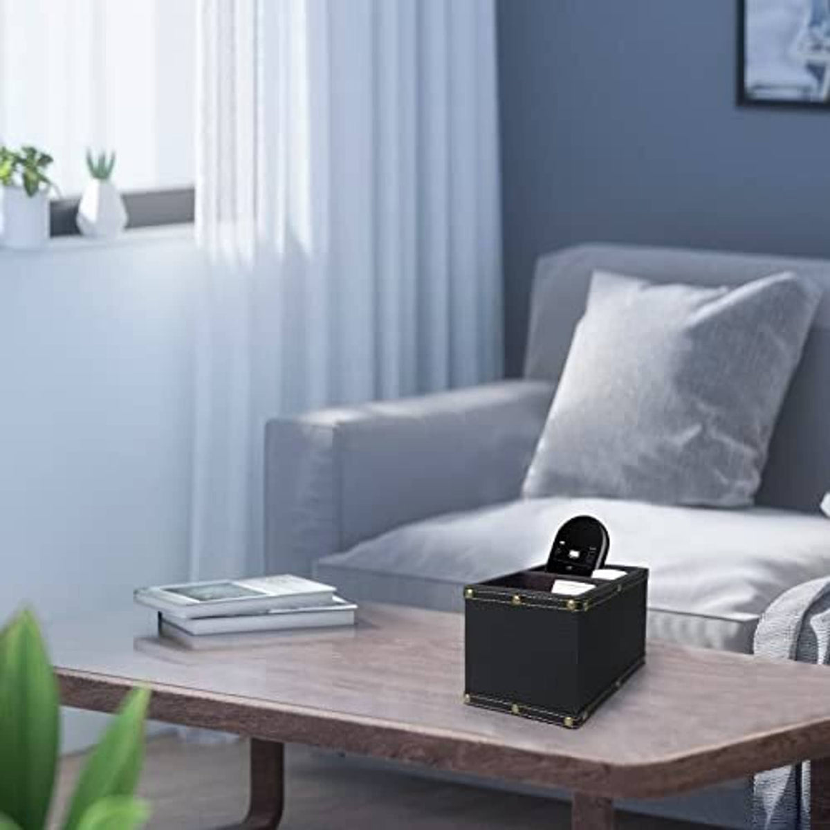 Black leather remote holder with open slot and brass-trim studs, placed on a table