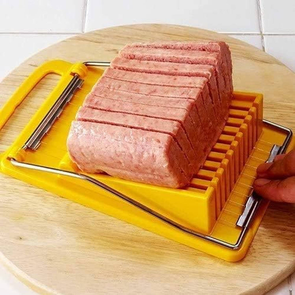 Yellow deli meat slicer on a wooden board, cutting a pink loaf into strips