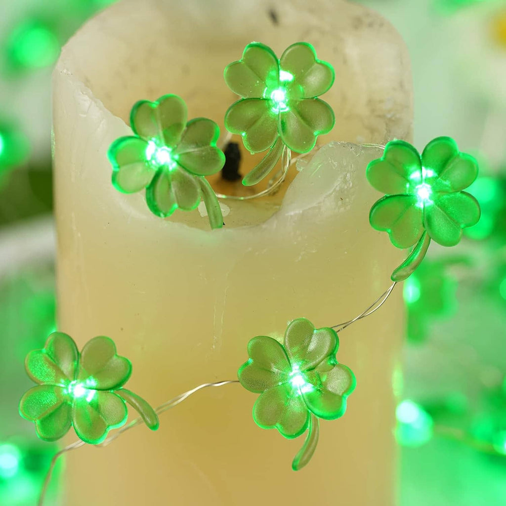 Green shamrock string lights with glowing clover LEDs wrapped around an icy candle