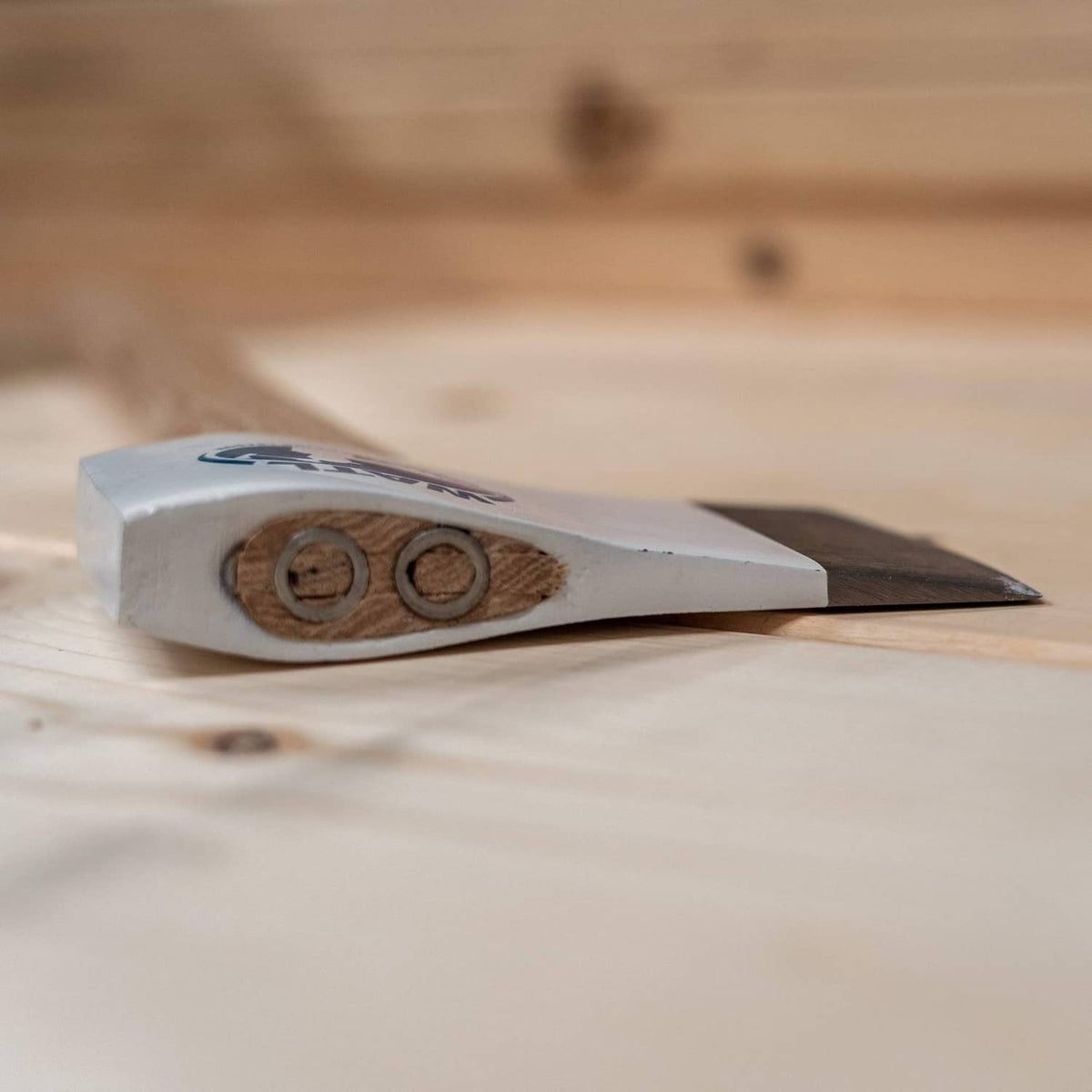 Axe blade tip on wood showing two circular inlays on the white head