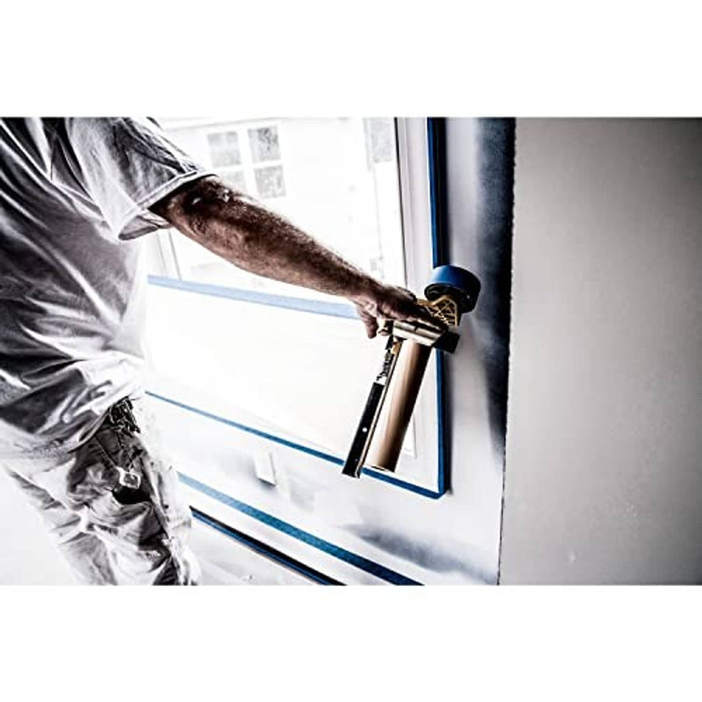 Painter spraying near blue tape masking around a door and frame