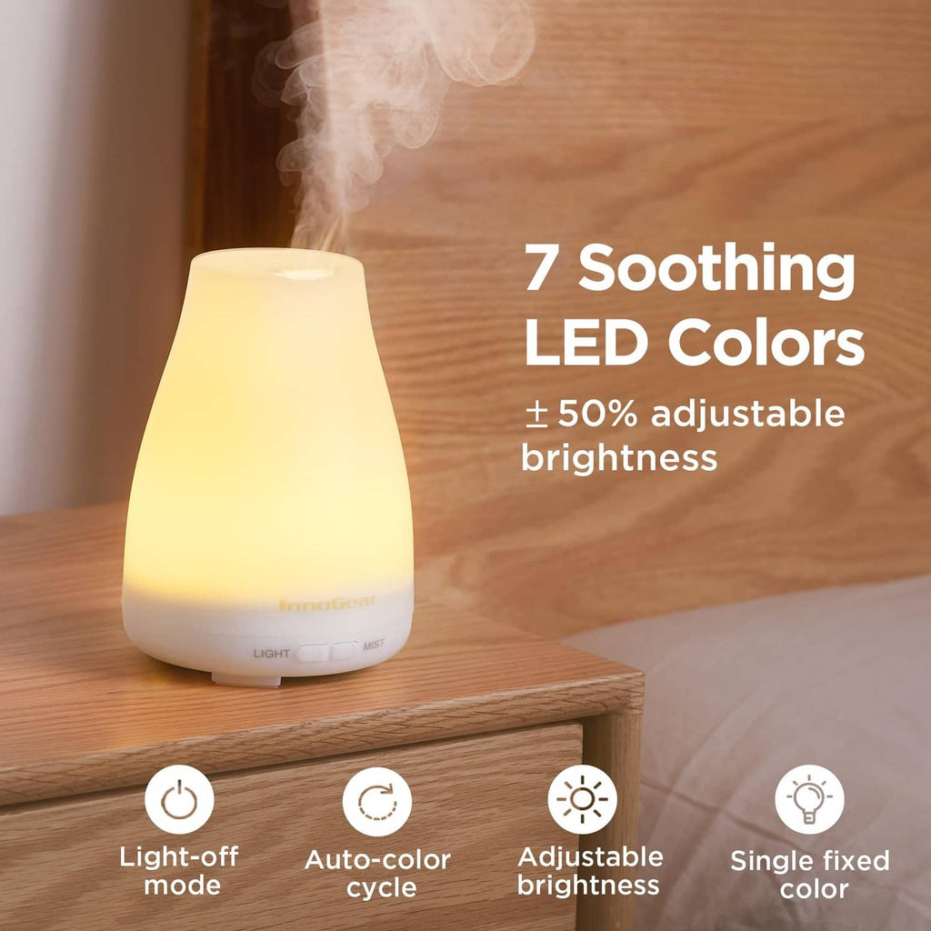 White essential oil diffuser with warm LED glow on wooden surface