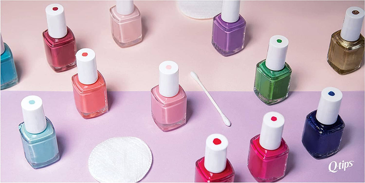Assorted nail polish bottles with cotton swabs on a pastel surface