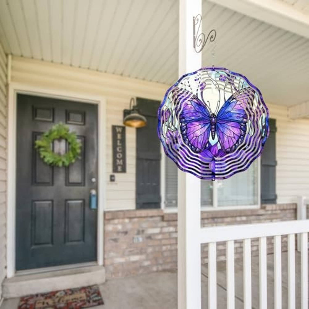 Purple butterfly wind spinner with white spiral rings hanging near porch ceiling
