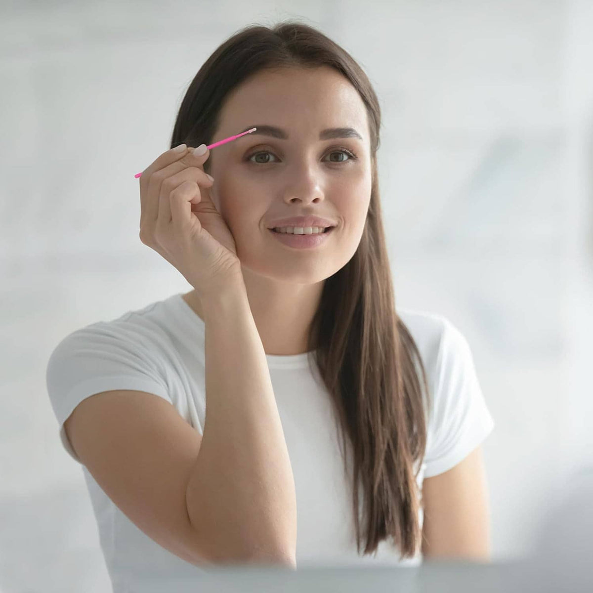 Pink micro swab held near the eye for precise makeup or lash application