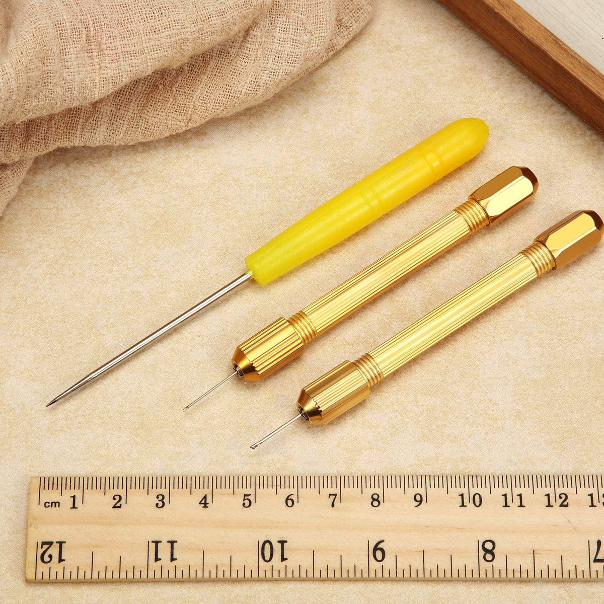 Gold doll hair rooting holders with long needles and yellow handle on work surface