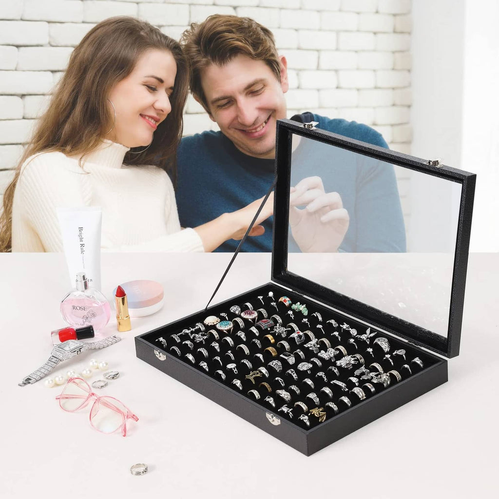 Open black ring storage case with clear lid showing rows of ring slots