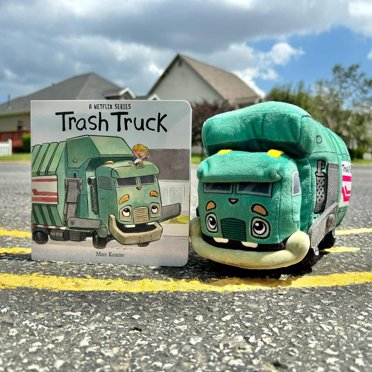 Green trash truck plush with friendly face and wheels, posed outdoors