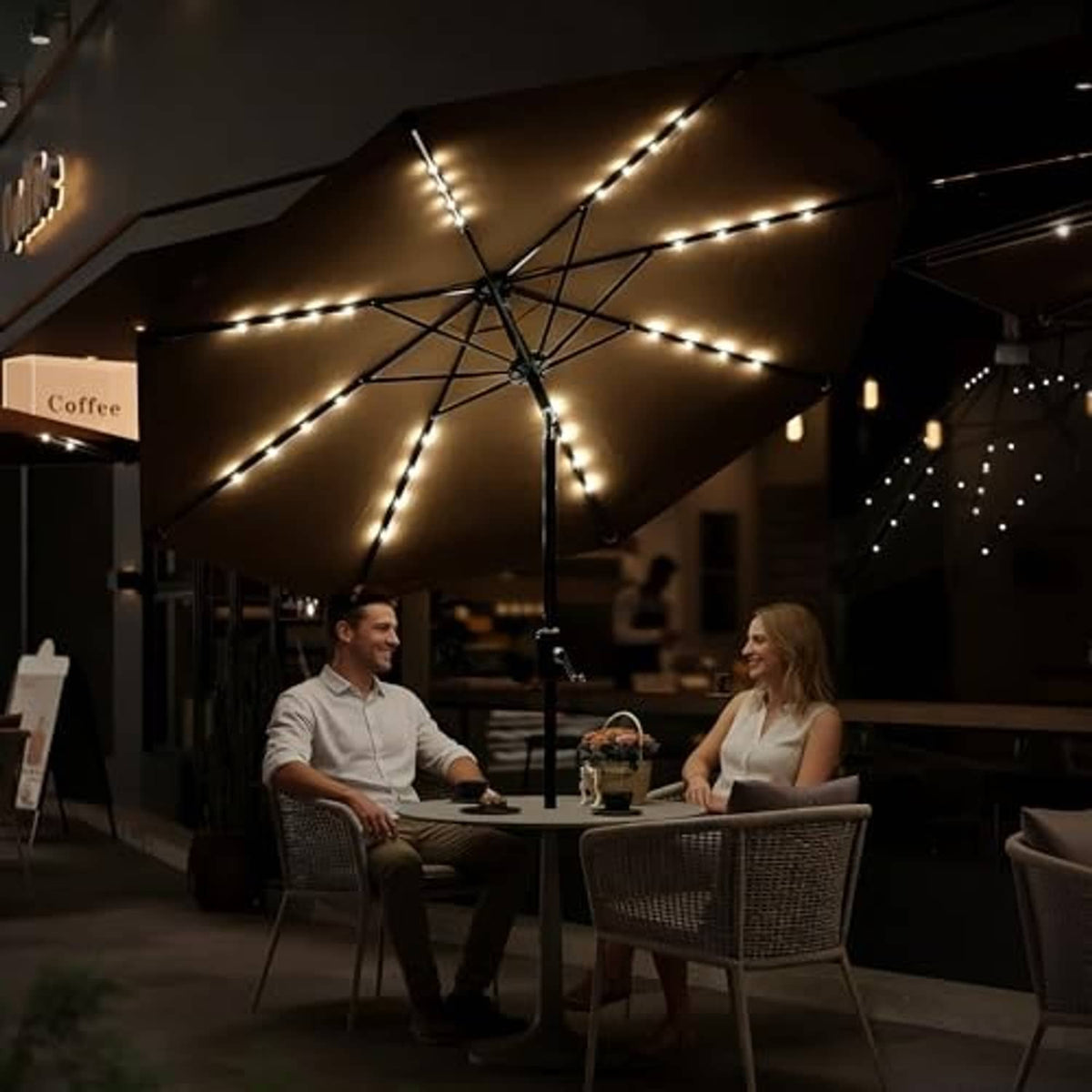 Tan outdoor umbrella with solar LED lights overhead above a patio dining table