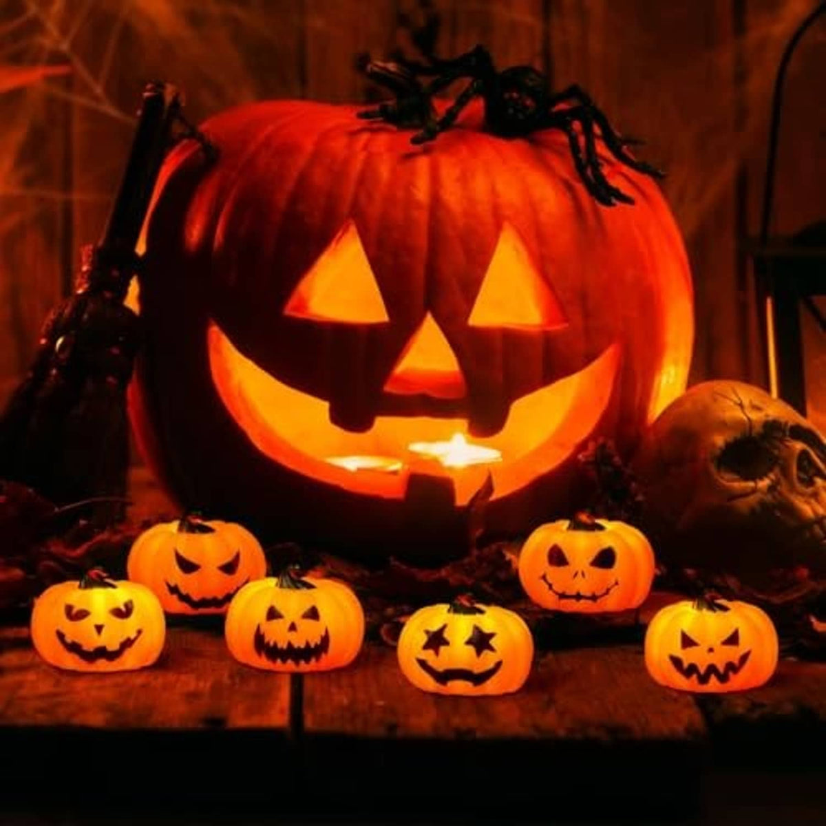 Glowing Halloween jack-o’-lantern pumpkin tea lights on a wooden display