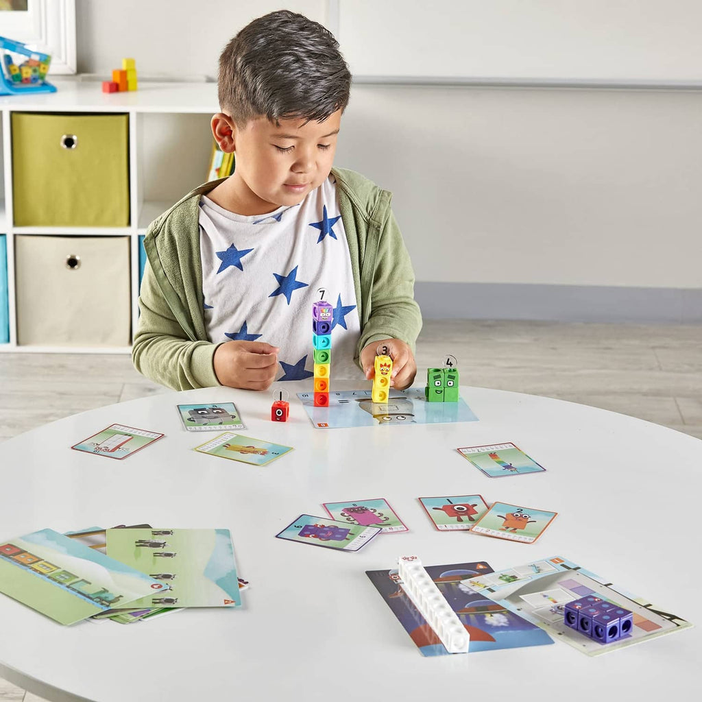 Child stacking Numberblocks cubes and arranging matching activity cards on a table