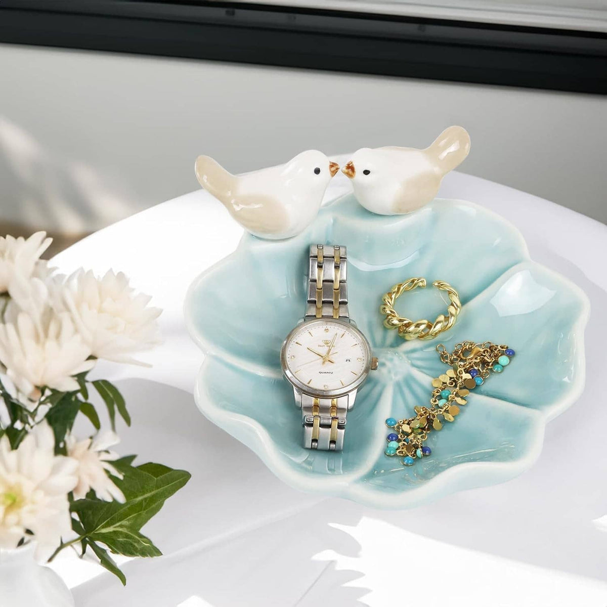 Ceramic lotus leaf jewelry tray with two white bird ring holders and assorted gold and blue jewelry