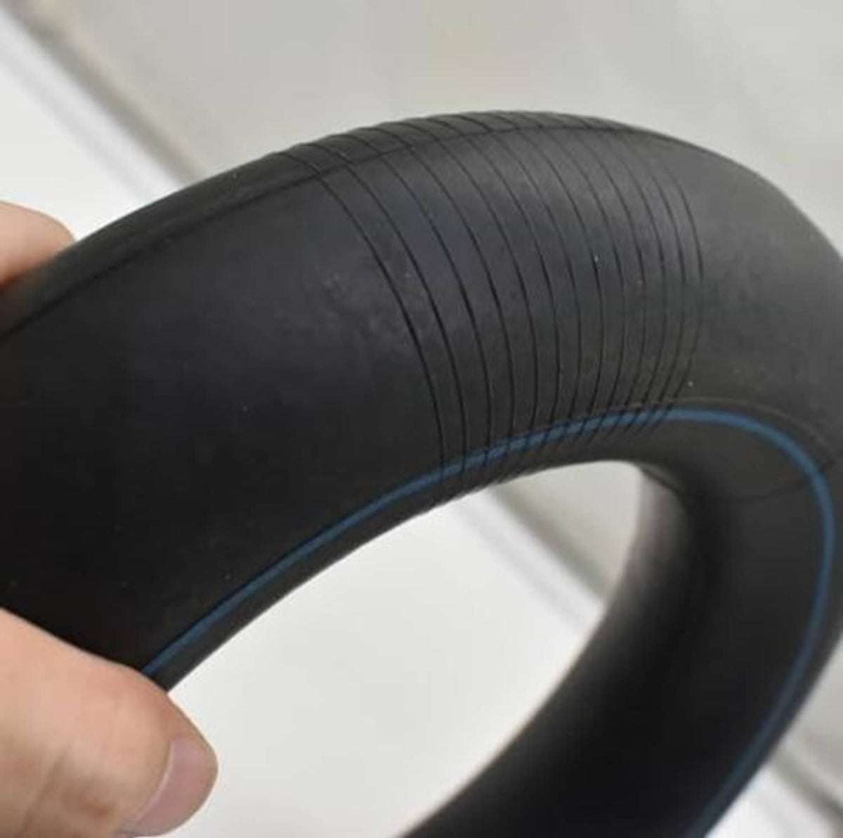 Black inner tube with blue seam line, held in hand; flexible rubber body.