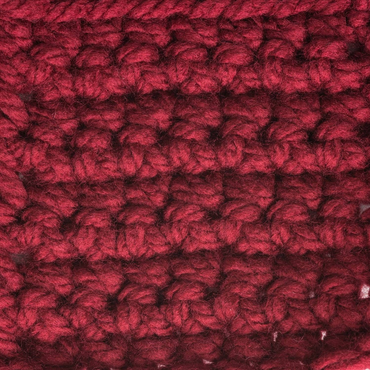 Close-up of deep red chunky acrylic yarn with dense, fluffy twisted texture
