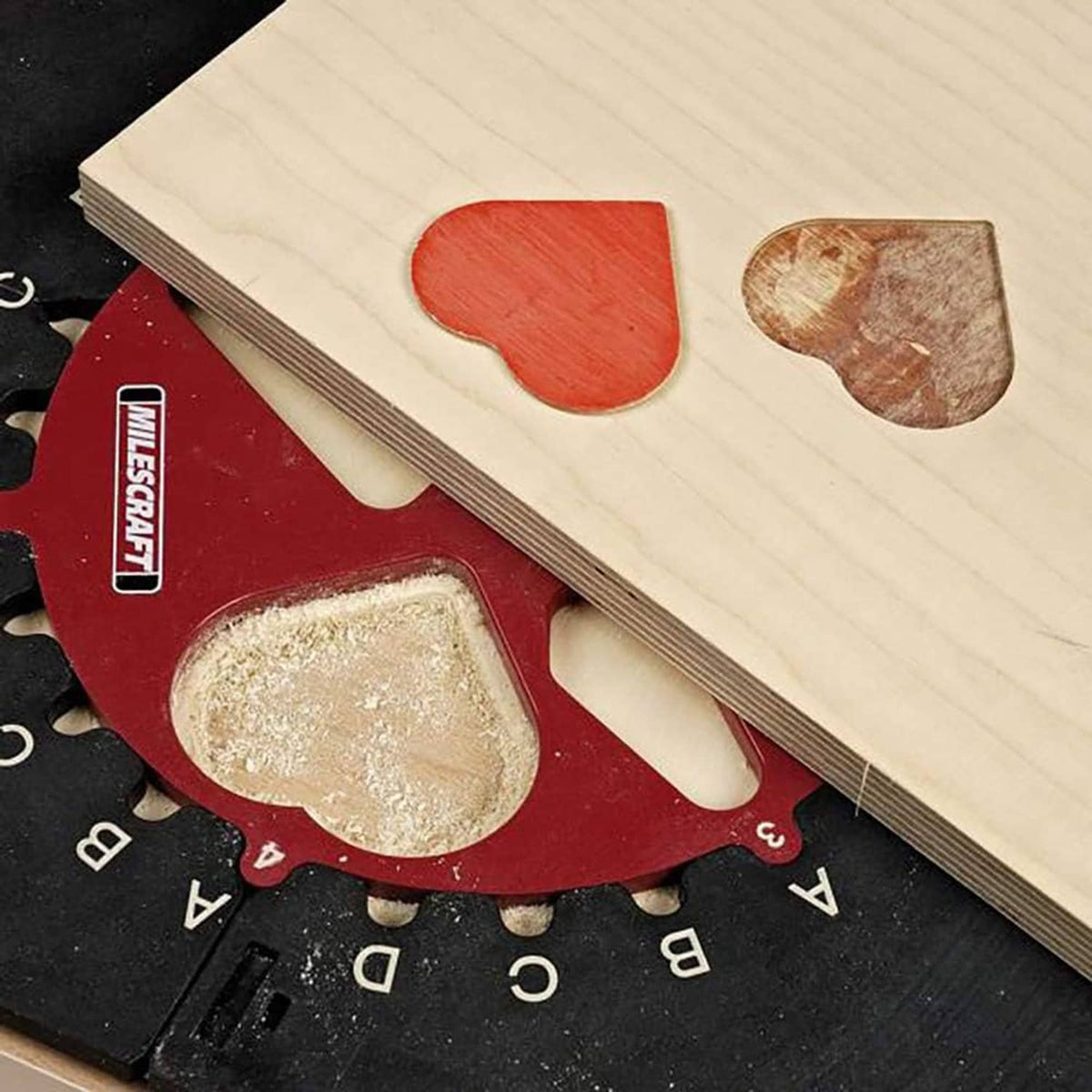 Red inlay template on black router jig base with light wood panel