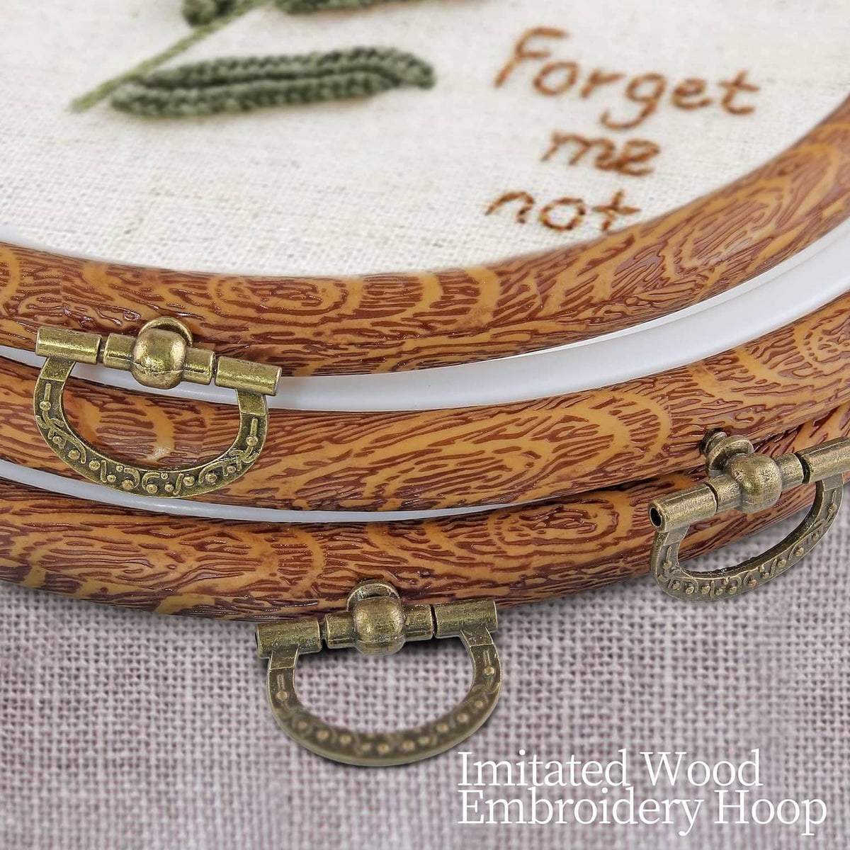 Wood-look embroidery hoop close-up with metal latch and white inner ring