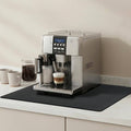 Black rectangular countertop drying mat under a coffee machine and cups