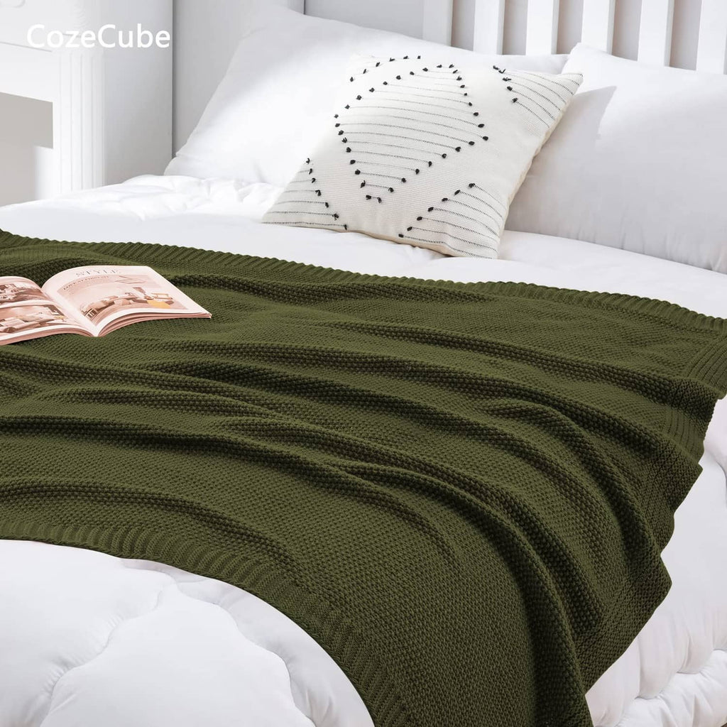 Olive green knit throw blanket draped across a bed for a layered look.