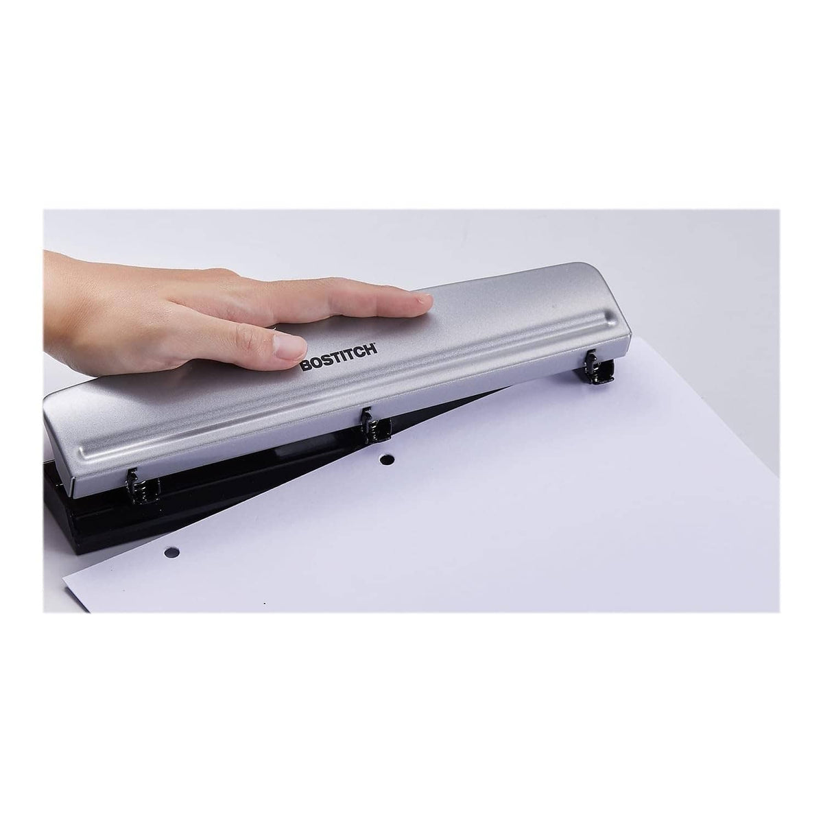 BOSTITCH 3-hole metal office punch held over white paper