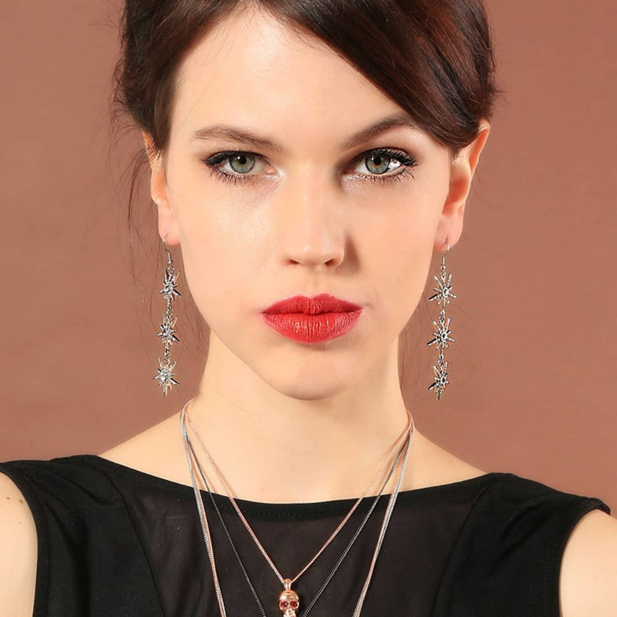 Snowflake dangle earrings on model, silver-toned drops with three snowflakes each