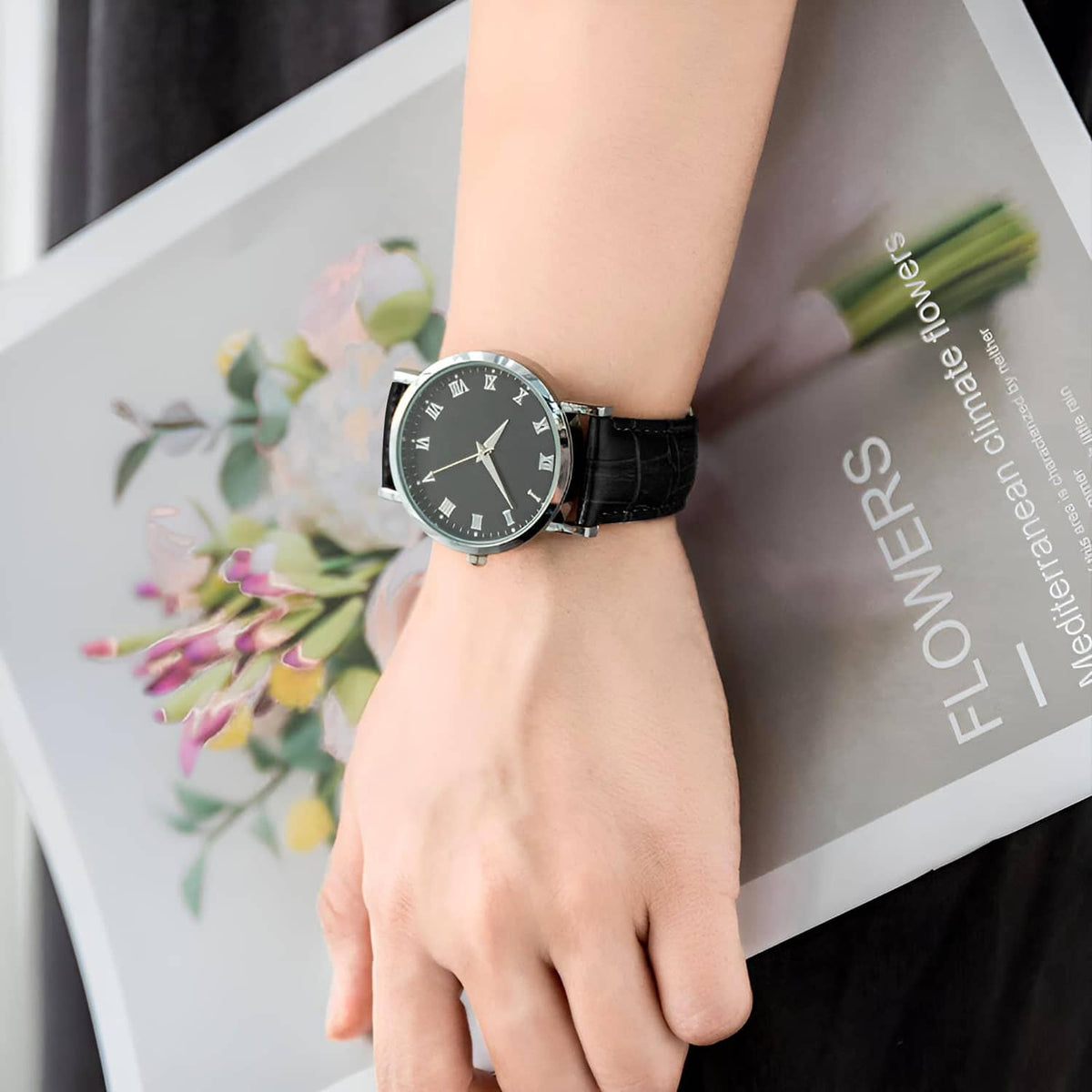 Black leather watch band on wrist with silver buckle clasp