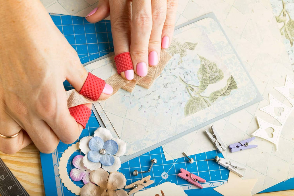 Red finger tip grip rings on fingertips while crafting on a cutting mat