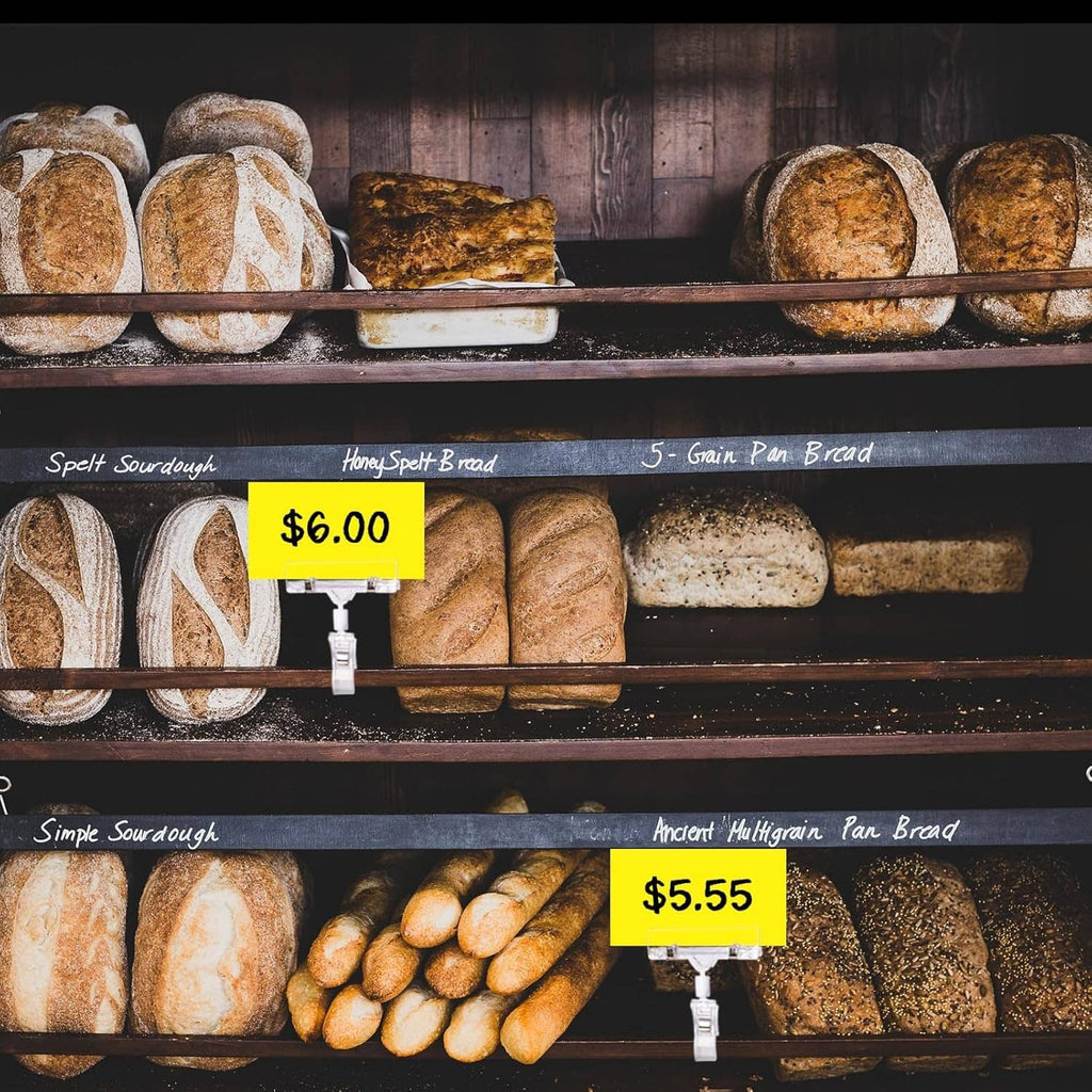 Clear sign holder clips holding price tags on a bakery bread display shelf