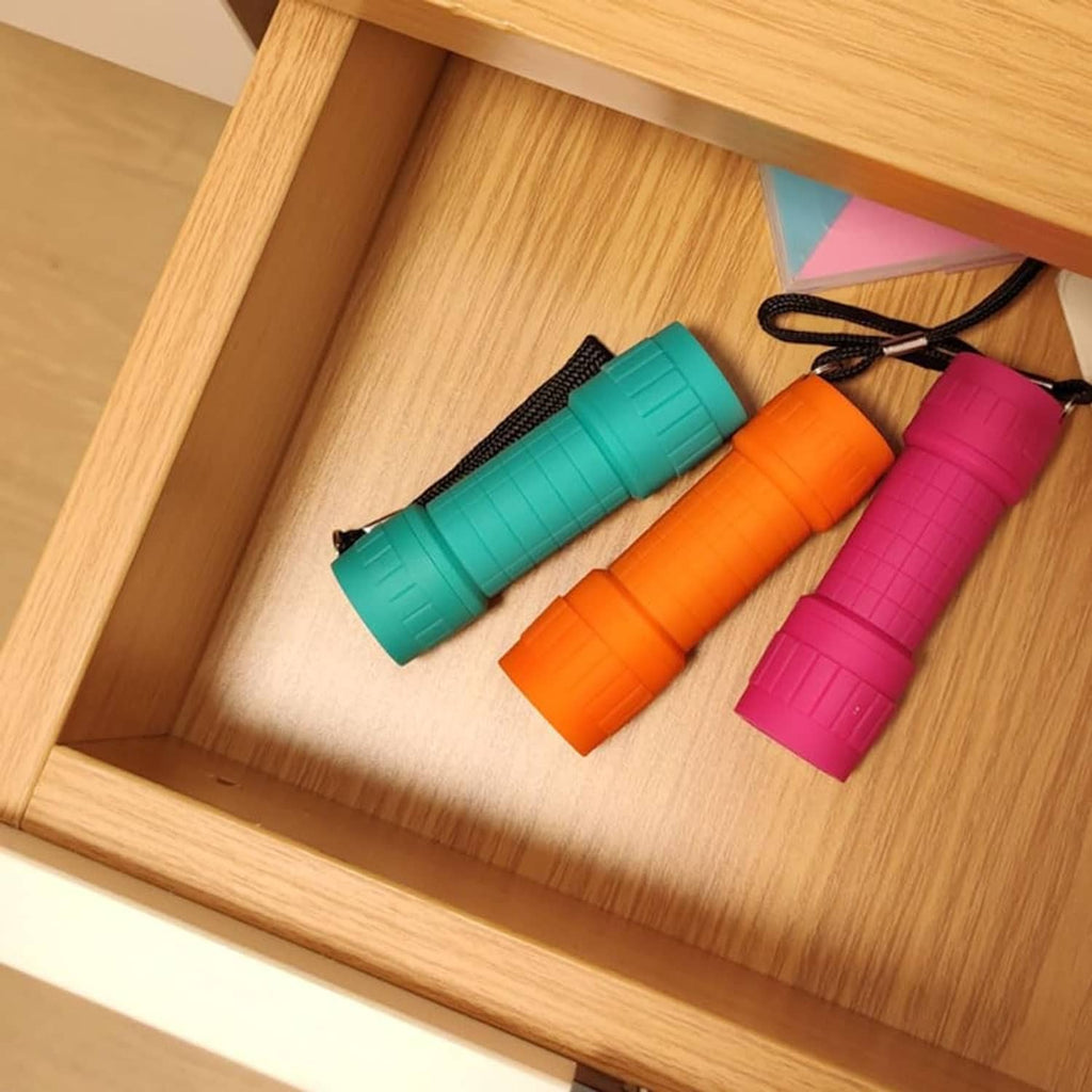 Teal, orange, and pink LED mini flashlights stored in a wooden drawer
