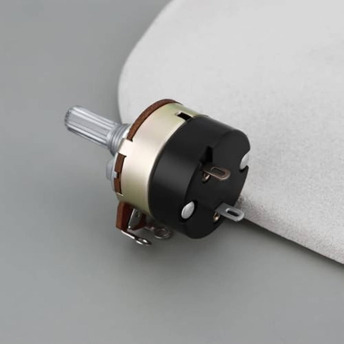 Rotary potentiometer on a surface with silver shaft and black front housing