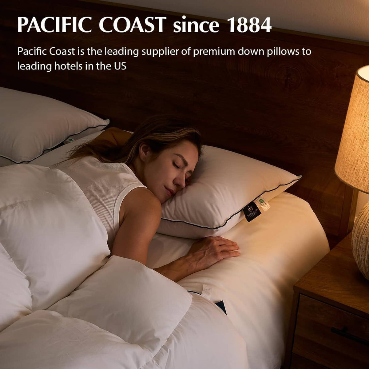 White down fiber pillows with dark piping on bed, person sleeping