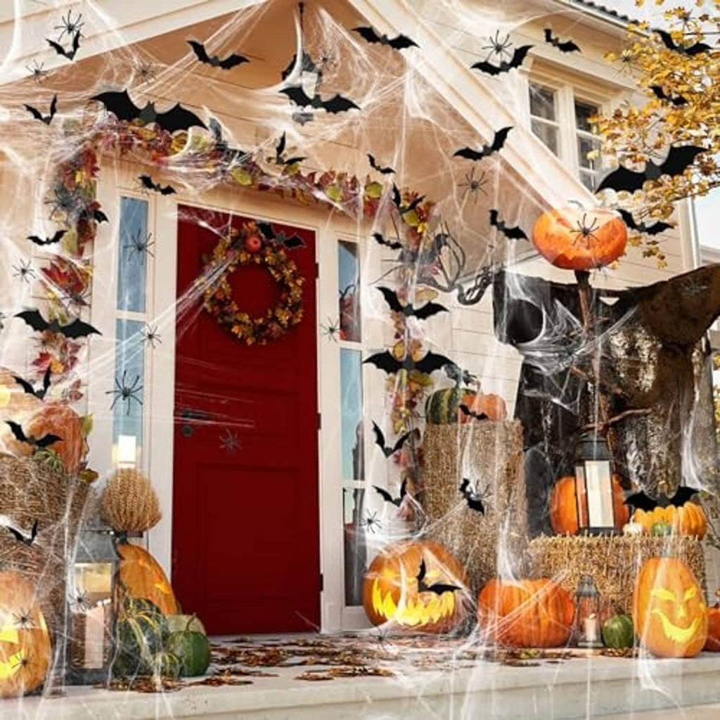 Halloween spider web decoration on a front porch with black bats, pumpkins, and hanging lights