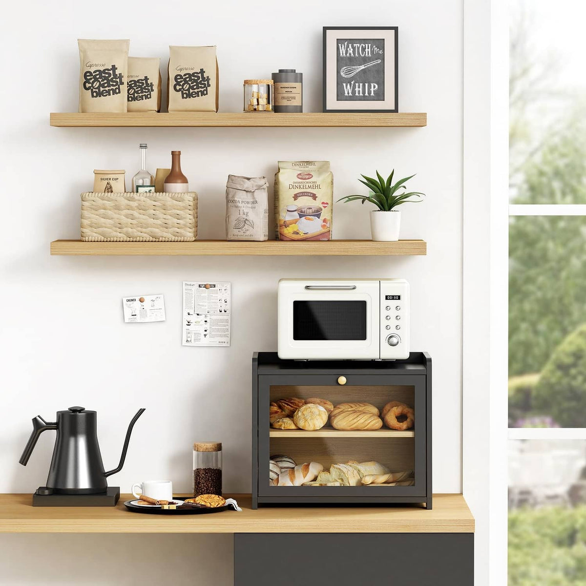 Black two-tier bread box on countertop with open front and breads on upper and lower shelves