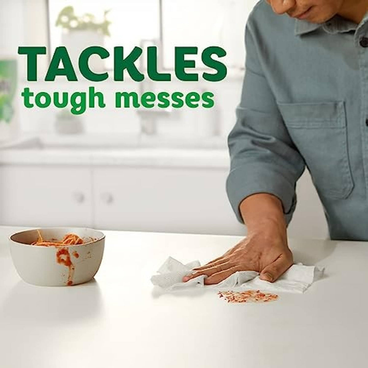 Paper towel being pulled for cleanup next to a bowl on a kitchen counter