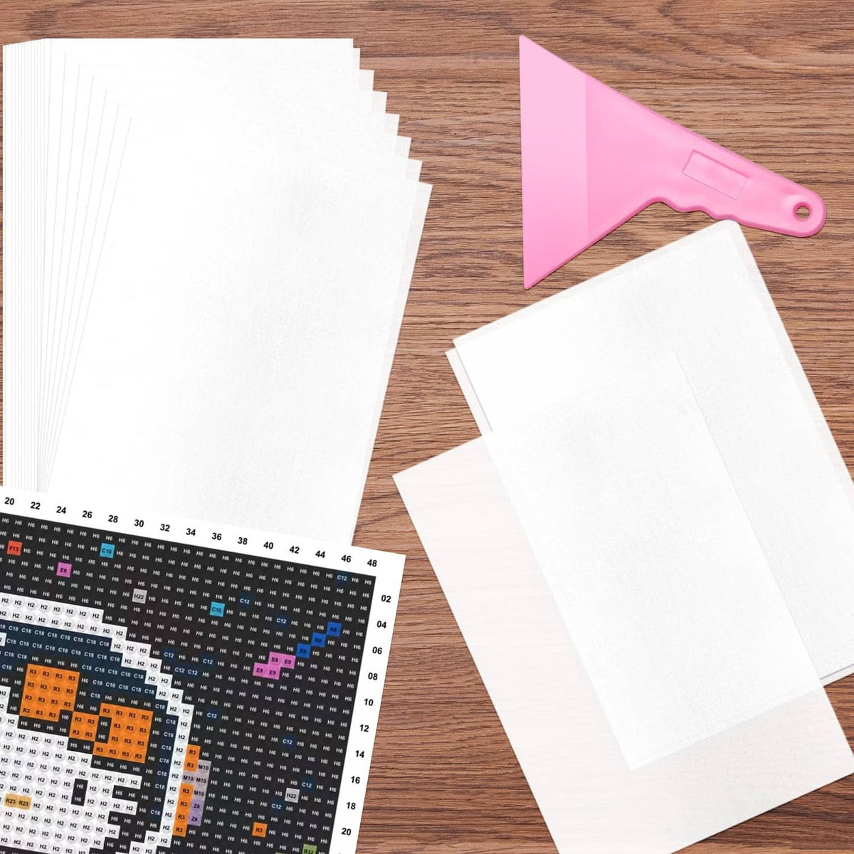 Stack of white double-sided release paper sheets with pink-handled scraper tool