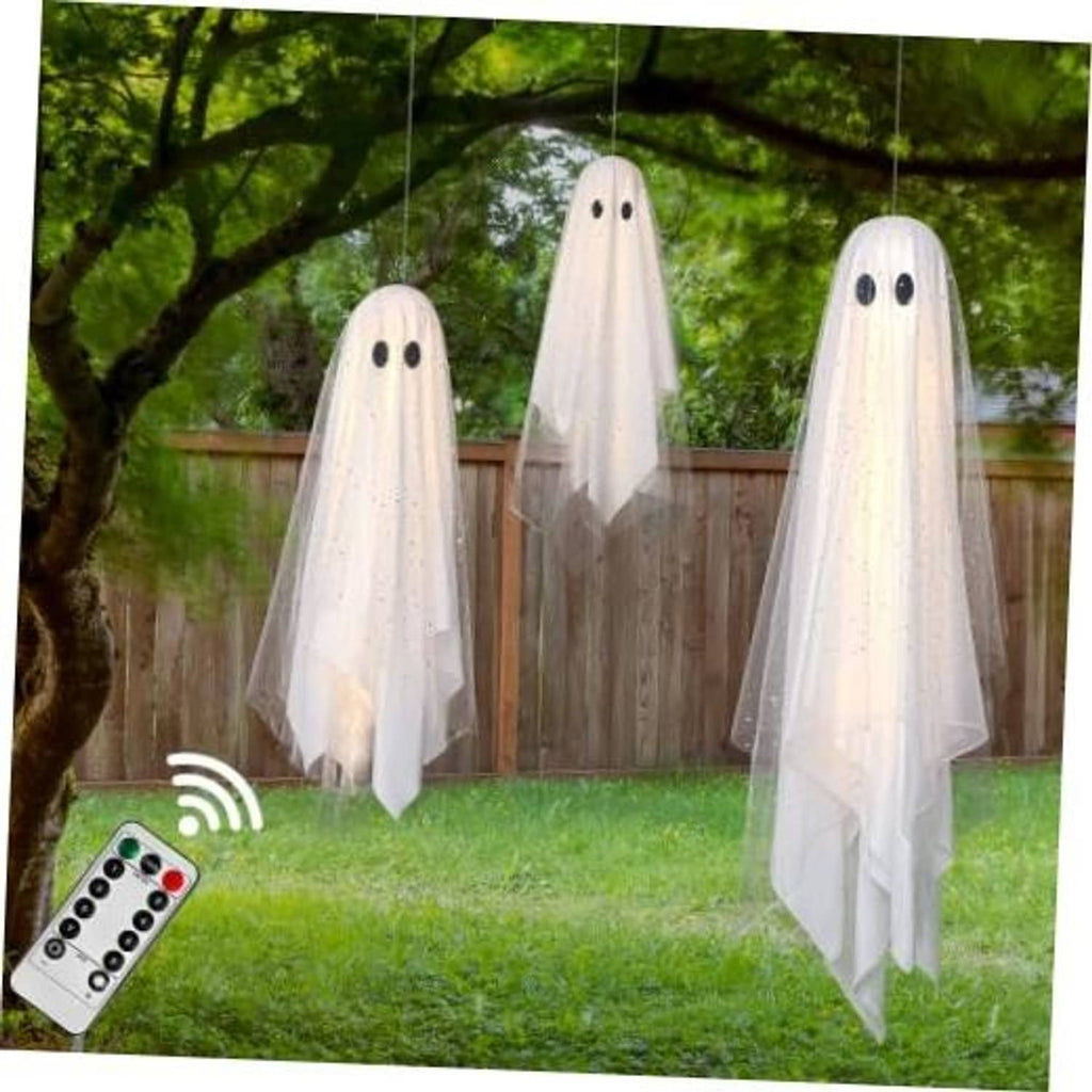 Three white hanging ghost decorations with black eyes and sheer tulle tails for yard decor