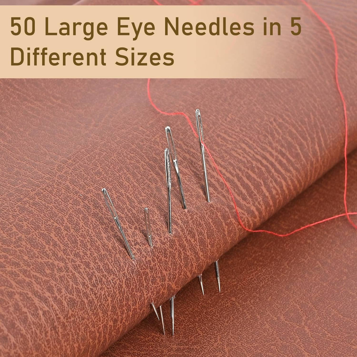 Silvery large-eye sewing needles laid on fabric, mixed lengths for different sizes