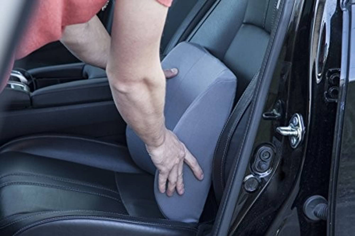 Gray lumbar support pillow on a vehicle seat, positioned between the backrest and chair base