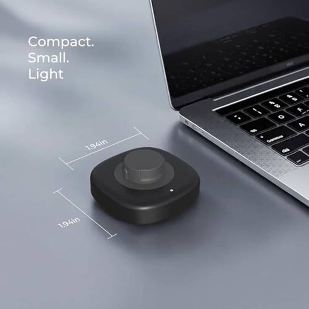 Compact dark gray charging dock with circular cradle on desktop near laptop